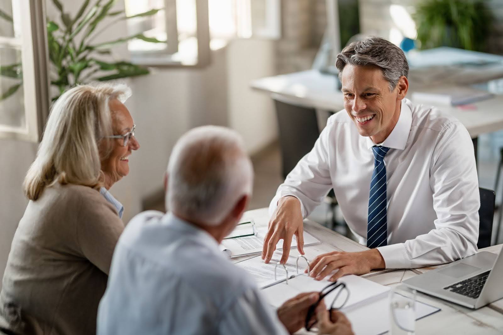Happy financial advisor communicating with mature couple in the office.