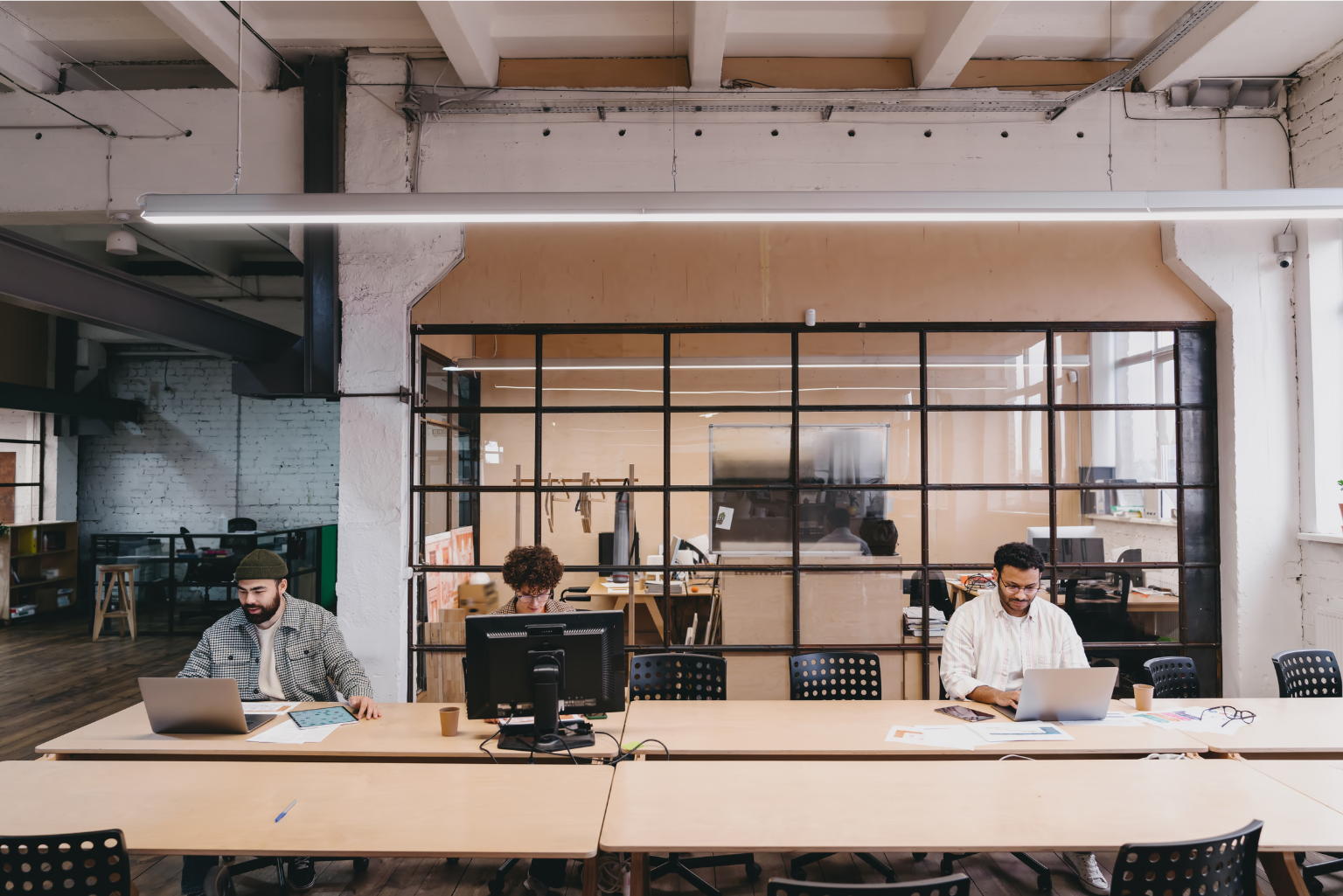 A calm, minimialist office workspace with employees working on laptops.