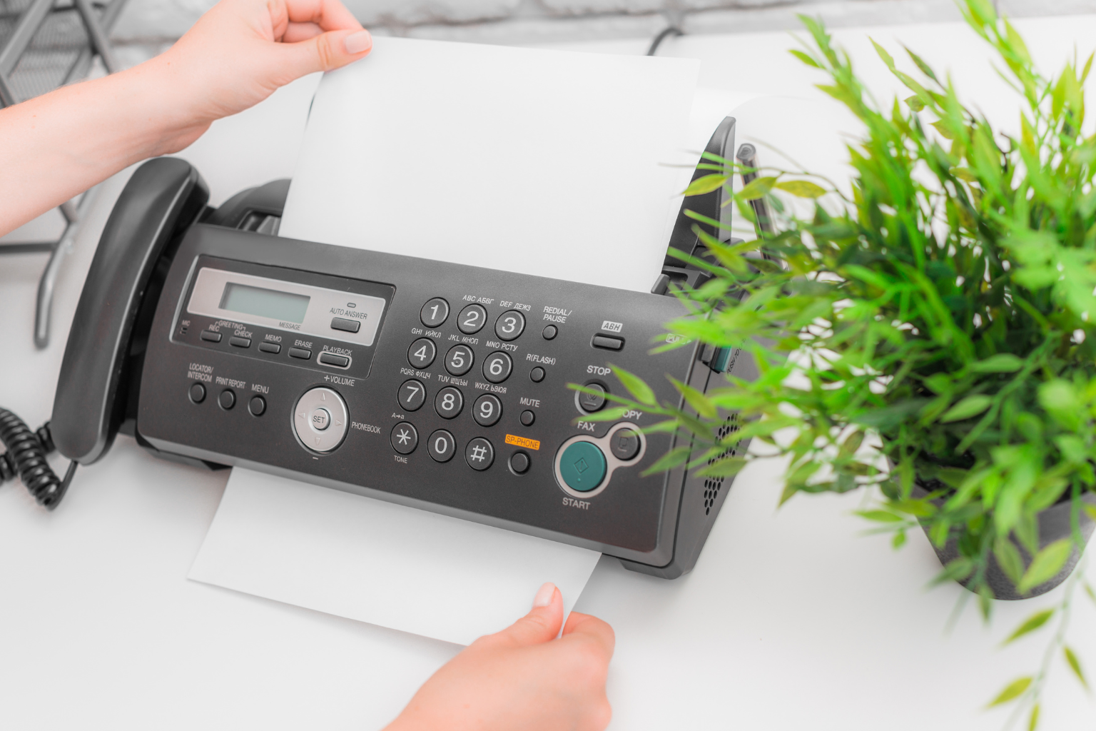 Close-up of a professional using a fax machine in an office.